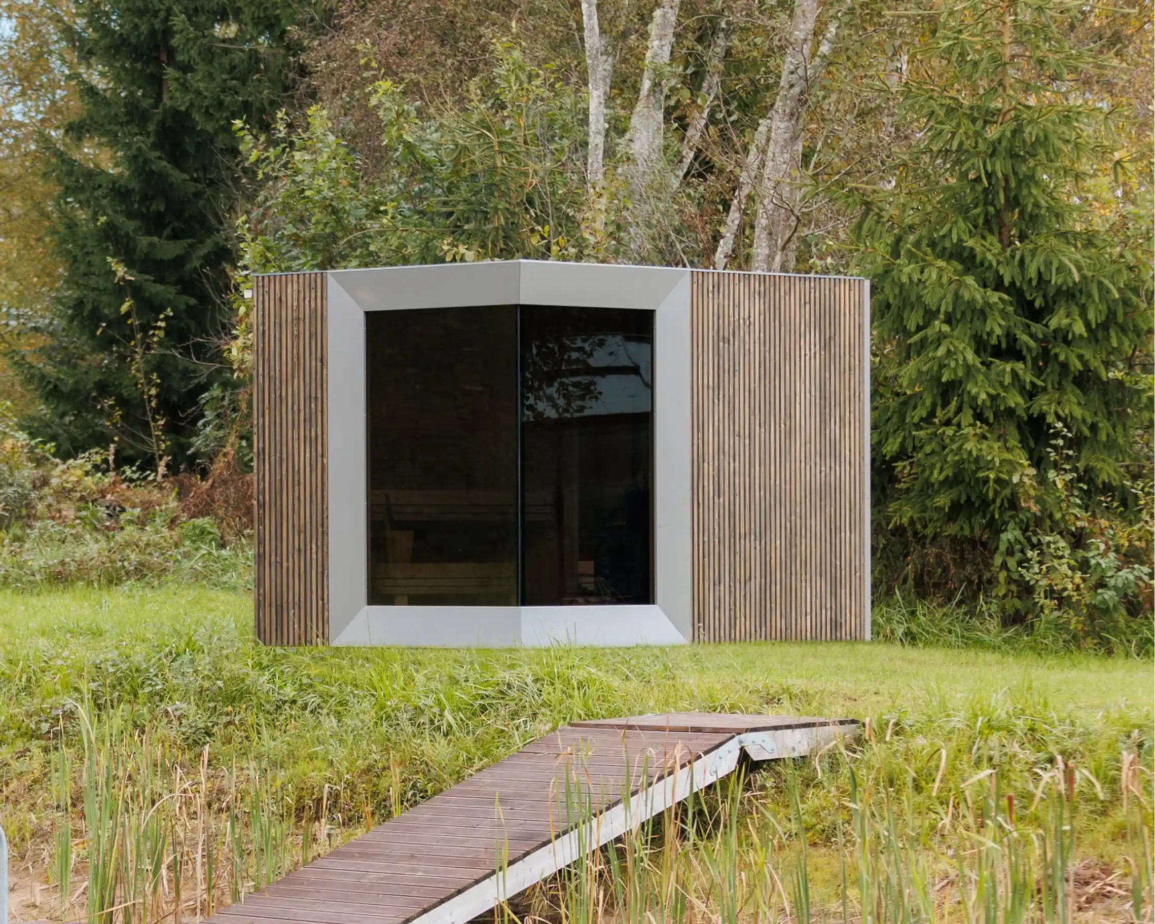 Modern wooden cabin by a lake with a dock in a forest setting