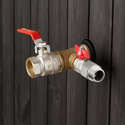 Brass valve with red handles attached to a black metal surface