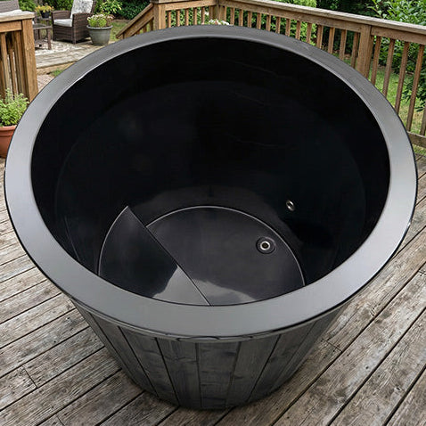 Black plastic planter on a wooden deck with outdoor furniture in the background